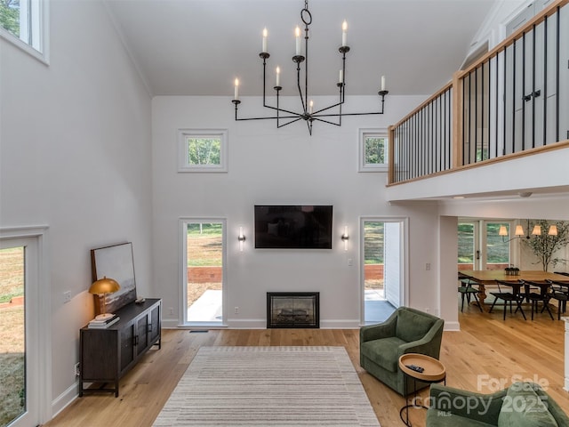 202 Walden Ln, Weddington, NC 28104 - living room featuring a chandelier, a high ceiling, wood finished floors, a glass covered fireplace, and plenty of natural light