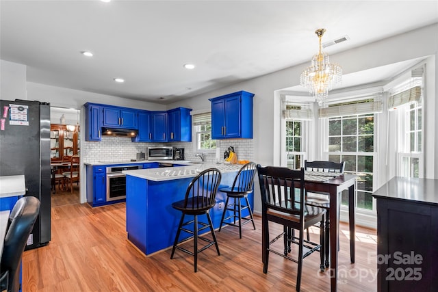 1109 Sunnyview Cir, Matthews, NC 28105 - kitchen with stainless steel appliances, blue cabinets, a chandelier, a peninsula, and light countertops