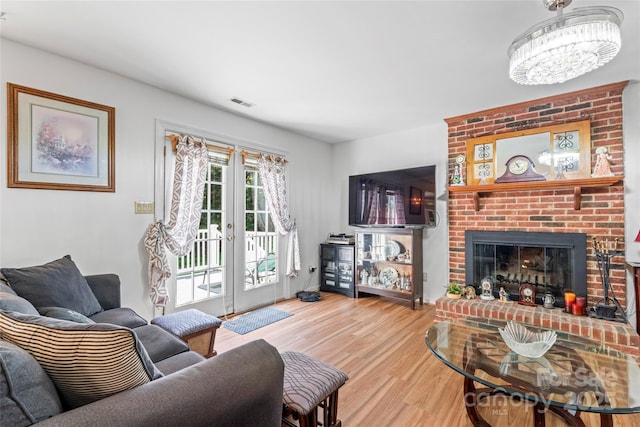 1109 Sunnyview Cir, Matthews, NC 28105 - living area with wood finished floors, a brick fireplace, and a chandelier