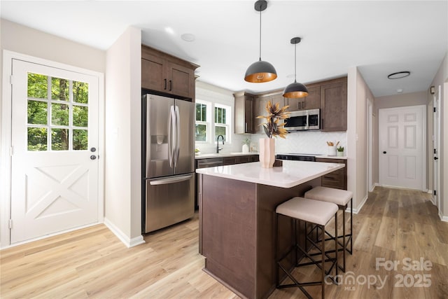 7407 Limerick Dr, Charlotte, NC 28270 - kitchen featuring appliances with stainless steel finishes, a kitchen breakfast bar, light countertops, backsplash, and light wood-type flooring