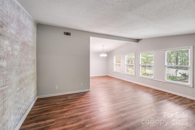 6513 Old Post Rd, Charlotte, NC 28212 - empty room with wood finished floors, a chandelier, a textured ceiling, and vaulted ceiling