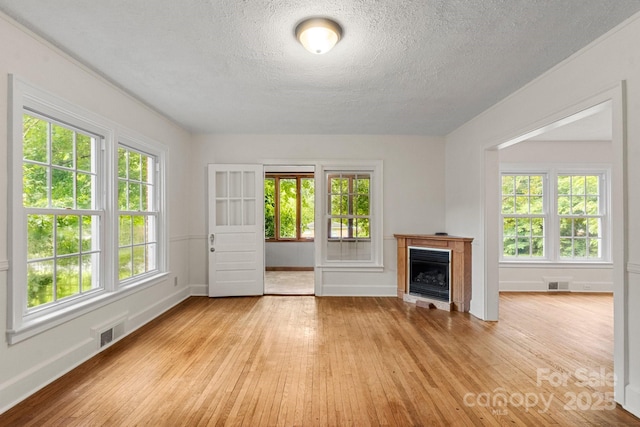 728 Blanton St, Shelby, NC 28150 - unfurnished living room with light wood finished floors, a textured ceiling, healthy amount of natural light, and a fireplace