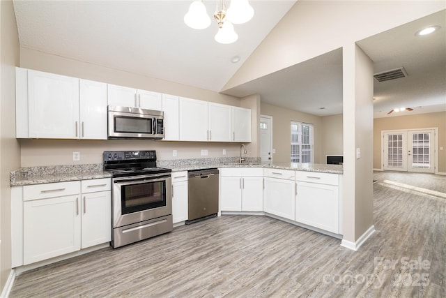 11531 Delores Ferguson Ln, Charlotte, NC 28277 - kitchen with appliances with stainless steel finishes, light wood-type flooring, white cabinetry, vaulted ceiling, and light stone countertops