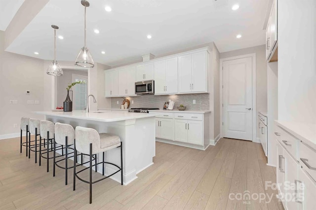 1074 Wylie Falls Ln, York, SC 29745 - kitchen featuring stainless steel microwave, light wood-type flooring, white cabinets, tasteful backsplash, and recessed lighting