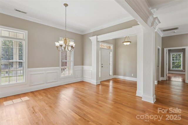 2411 Stoney Run Dr Unit 13, Oakboro, NC 28129 - spare room featuring ornate columns, light wood-type flooring, ornamental molding, a chandelier, and wainscoting