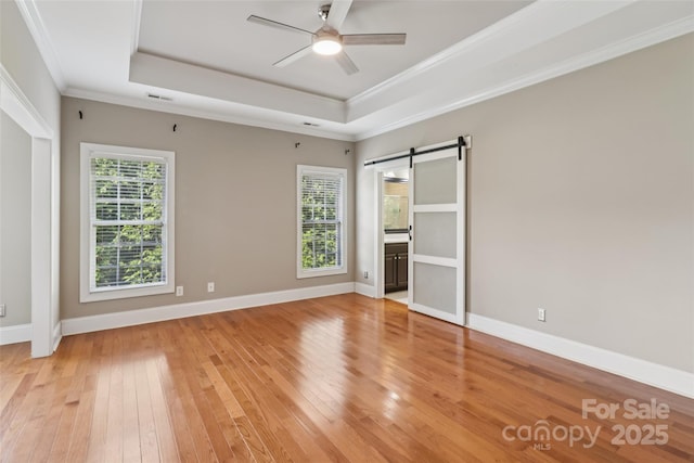 2411 Stoney Run Dr Unit 13, Oakboro, NC 28129 - unfurnished bedroom featuring a raised ceiling, a barn door, light wood-style flooring, ornamental molding, and ensuite bath