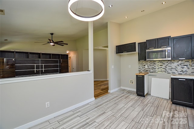 1312 Shenandoah Cir, Rock Hill, SC 29730 - kitchen featuring stainless steel microwave, a ceiling fan, backsplash, light wood-type flooring, and dark cabinetry