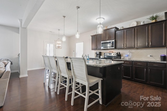 212 Fesperman Cir, Troutman, NC 28166 - kitchen featuring stainless steel appliances, light stone counters, a kitchen breakfast bar, dark wood finished floors, and dark brown cabinetry