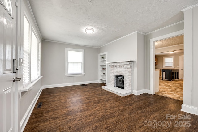 903 Rhode Island Ave, Kannapolis, NC 28083 - unfurnished living room with dark wood-style flooring, a textured ceiling, a brick fireplace, built in shelves, and ornamental molding