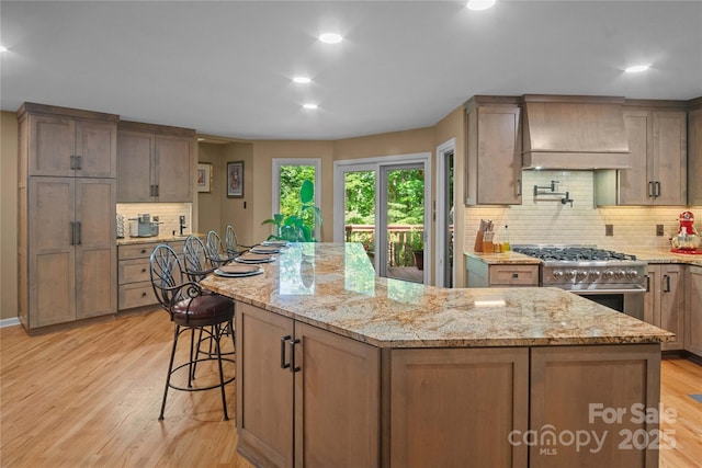 270 Foxwood Dr, Tryon, NC 28782 - kitchen featuring premium range hood, stainless steel range, a kitchen island, decorative backsplash, and light stone countertops