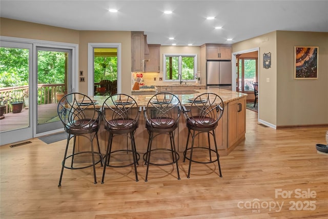 270 Foxwood Dr, Tryon, NC 28782 - kitchen featuring freestanding refrigerator, a kitchen breakfast bar, light wood-style floors, tasteful backsplash, and light stone countertops