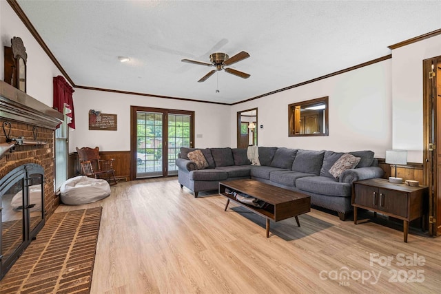 36433 Azalea Cir, New London, NC 28127 - living area featuring crown molding, light wood-style floors, a ceiling fan, wainscoting, and a brick fireplace