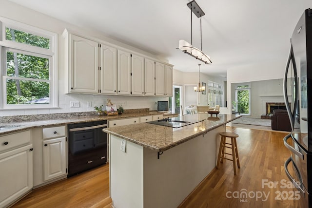 4716 Heatherton Pl, Charlotte, NC 28270 - kitchen with black appliances, a breakfast bar area, open floor plan, light wood-style floors, and white cabinets