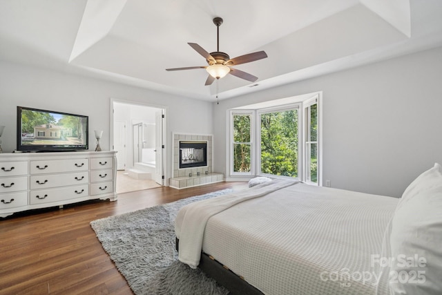 4716 Heatherton Pl, Charlotte, NC 28270 - bedroom featuring dark wood-style flooring, a tray ceiling, a fireplace, ceiling fan, and connected bathroom