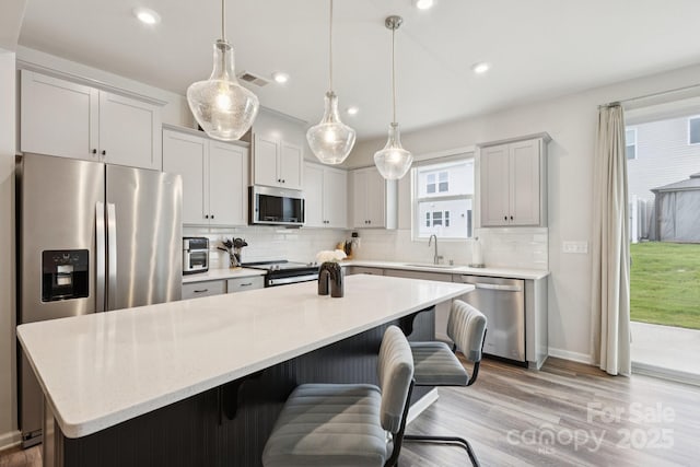 13323 Savaine St, Charlotte, NC 28278 - kitchen featuring stainless steel appliances, backsplash, a kitchen island, recessed lighting, and a kitchen breakfast bar