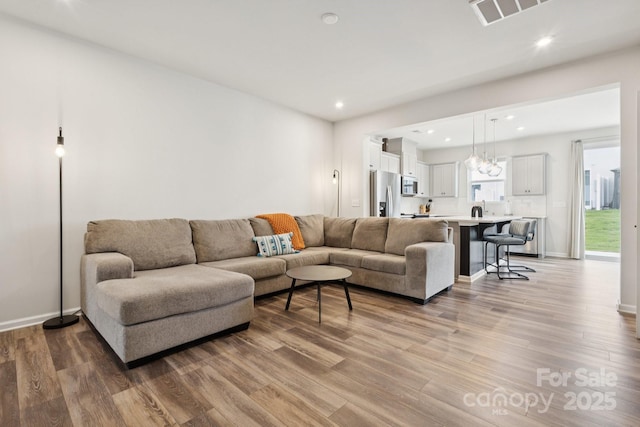 13323 Savaine St, Charlotte, NC 28278 - living room with light wood-type flooring, recessed lighting, and a chandelier