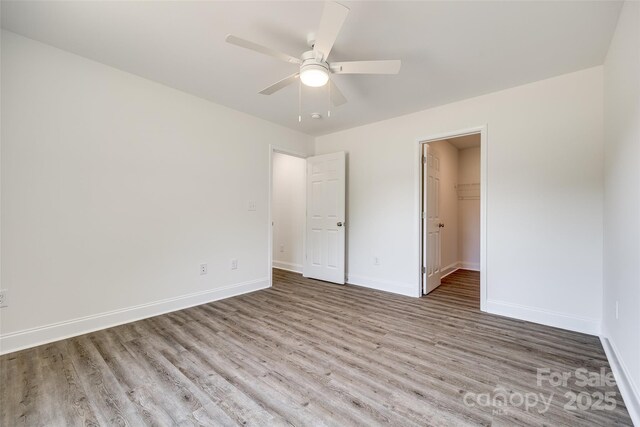 3248 Ferguson Long Rd, York, SC 29745 - unfurnished bedroom with wood finished floors, a spacious closet, a ceiling fan, and a closet