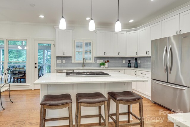 5051 Carillon Way, Charlotte, NC 28270 - kitchen featuring appliances with stainless steel finishes, white cabinetry, backsplash, a breakfast bar area, and crown molding