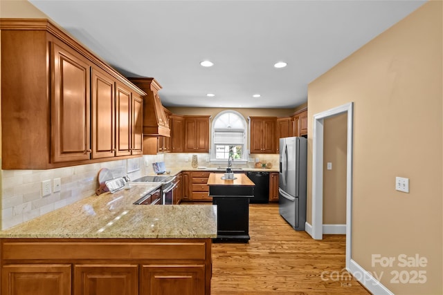 1019 Westlake Dr, Kannapolis, NC 28081 - kitchen with stainless steel appliances, light wood-style floors, light stone counters, decorative backsplash, and a peninsula