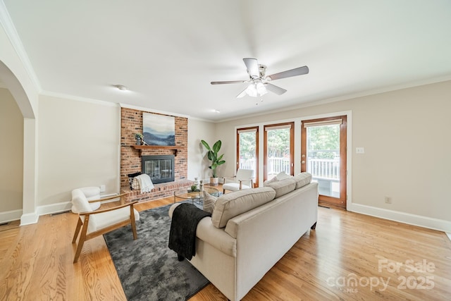6412 Boykin Spaniel Rd, Charlotte, NC 28277 - living area featuring a ceiling fan, arched walkways, a brick fireplace, light wood-type flooring, and crown molding