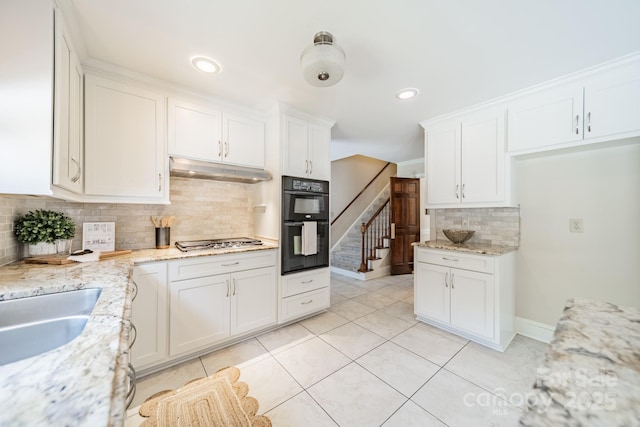 6412 Boykin Spaniel Rd, Charlotte, NC 28277 - kitchen with under cabinet range hood, tasteful backsplash, white cabinets, stainless steel gas stovetop, and light tile patterned floors