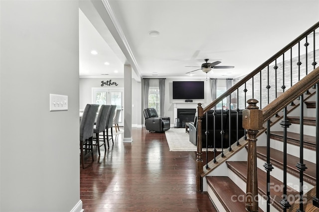 2377 Maple Grove Ln NW, Concord, NC 28027 - staircase with crown molding, wood-type flooring, a ceiling fan, and a glass covered fireplace