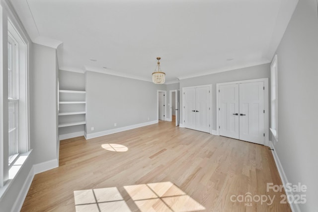 4349 Castleton Rd, Charlotte, NC 28211 - unfurnished bedroom with two closets, light wood finished floors, ornamental molding, and a chandelier