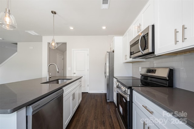 1209 Cathey Rd, Charlotte, NC 28214 - kitchen featuring appliances with stainless steel finishes, backsplash, white cabinets, dark wood finished floors, and a center island with sink