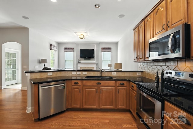 10818 Alvarado Way, Charlotte, NC 28277 - kitchen with stainless steel appliances, a peninsula, dark stone countertops, light wood-style flooring, and recessed lighting
