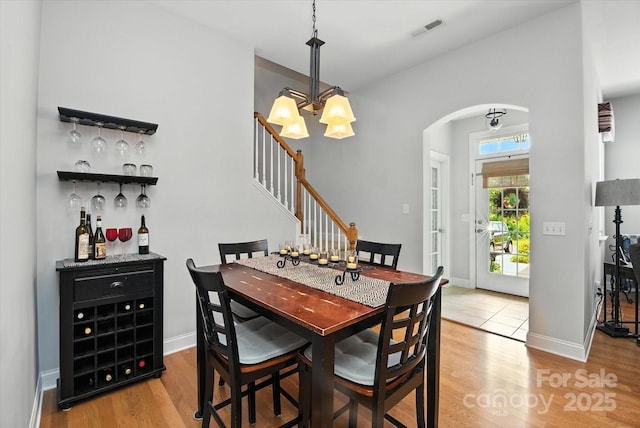 10818 Alvarado Way, Charlotte, NC 28277 - dining area with arched walkways, a chandelier, light wood-type flooring, stairs, and a dry bar