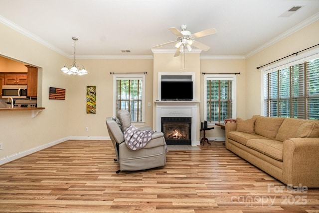 2773 Clover Rd NW, Concord, NC 28027 - living area featuring light wood-style floors, a fireplace with flush hearth, a ceiling fan, ornamental molding, and a chandelier