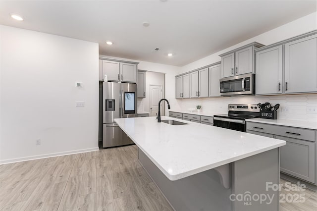 5010 Arbordale Way, Mount Holly, NC 28120 - kitchen with appliances with stainless steel finishes, gray cabinetry, a center island with sink, light wood-style floors, and recessed lighting