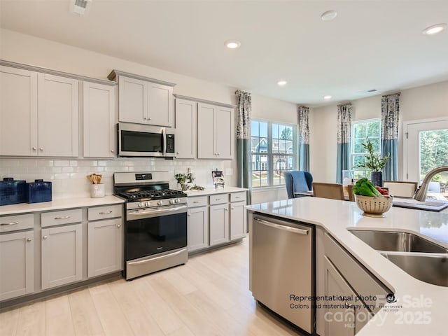 1020 Lookout Shoals Dr, Fort Mill, SC 29715 - kitchen featuring stainless steel appliances, gray cabinets, light countertops, decorative backsplash, and light wood-style flooring