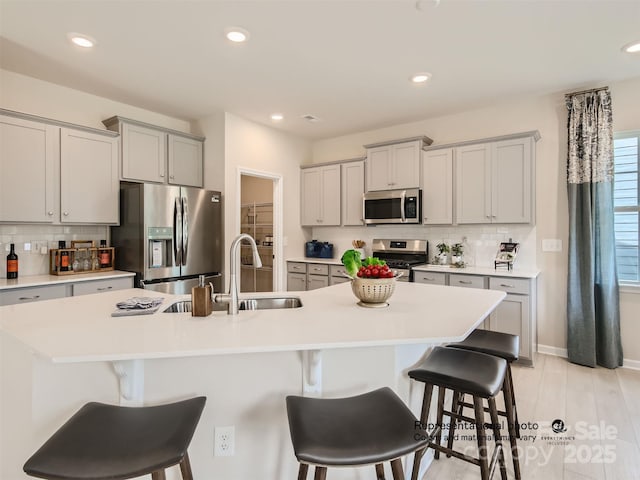 1020 Lookout Shoals Dr, Fort Mill, SC 29715 - kitchen with stainless steel appliances, gray cabinetry, a breakfast bar, decorative backsplash, and recessed lighting