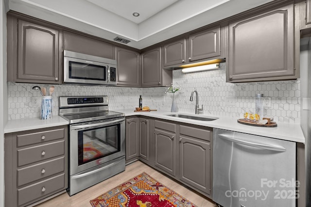4208 Burning Tree Dr, Charlotte, NC 28277 - kitchen featuring appliances with stainless steel finishes, decorative backsplash, light countertops, light wood finished floors, and gray cabinetry