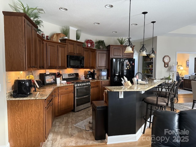 860 Wynnshire Dr, Hickory, NC 28601 - kitchen featuring black appliances, a kitchen breakfast bar, an island with sink, light stone countertops, and recessed lighting