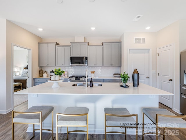 1016 Lookout Shoals Dr, Fort Mill, SC 29715 - kitchen featuring stainless steel appliances, gray cabinetry, a breakfast bar area, tasteful backsplash, and wood finished floors