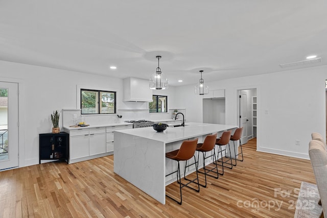 4209 Windwood Cir, Charlotte, NC 28226 - kitchen with white cabinetry, light wood-type flooring, recessed lighting, a kitchen bar, and hanging light fixtures