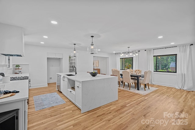 4209 Windwood Cir, Charlotte, NC 28226 - kitchen featuring light wood finished floors, recessed lighting, decorative light fixtures, white cabinets, and a kitchen island with sink