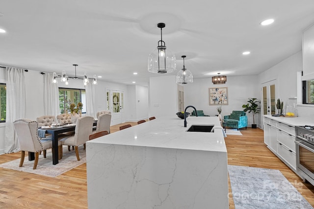 4209 Windwood Cir, Charlotte, NC 28226 - kitchen with stainless steel range, recessed lighting, light wood-style flooring, white cabinets, and an island with sink