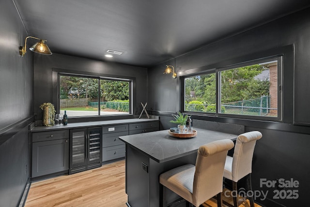 4209 Windwood Cir, Charlotte, NC 28226 - kitchen featuring wine cooler, healthy amount of natural light, light wood-type flooring, and gray cabinetry