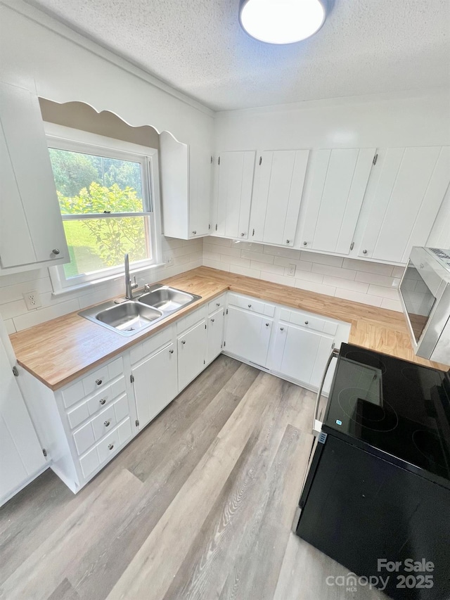 1678 Nelson Dr, Newton, NC 28658 - kitchen with electric range, a textured ceiling, light wood-style floors, wooden counters, and decorative backsplash
