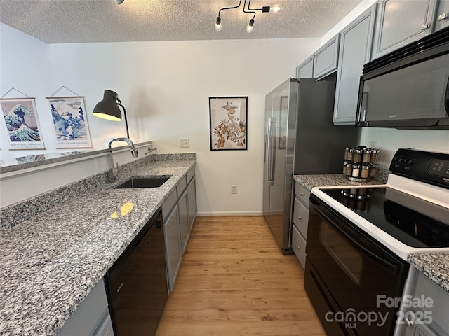215 Linkside Ct SE, Lenoir, NC 28645 - kitchen with black appliances, light wood-type flooring, gray cabinetry, a textured ceiling, and light stone countertops