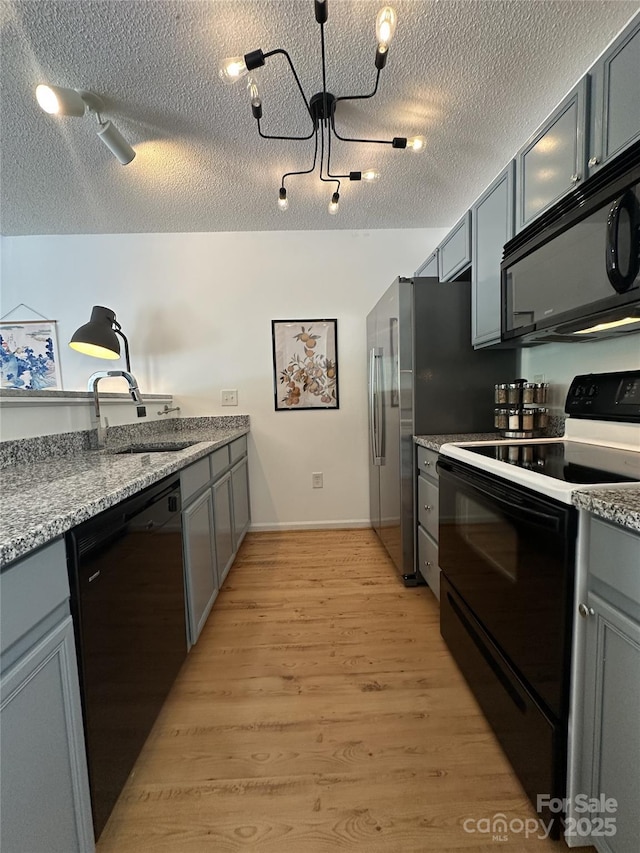 215 Linkside Ct SE, Lenoir, NC 28645 - kitchen featuring black appliances, light wood-style flooring, gray cabinets, a textured ceiling, and light stone countertops