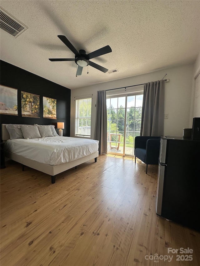 215 Linkside Ct SE, Lenoir, NC 28645 - bedroom featuring a textured ceiling, freestanding refrigerator, access to exterior, light wood finished floors, and ceiling fan