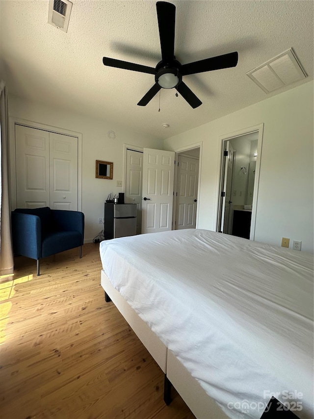 215 Linkside Ct SE, Lenoir, NC 28645 - bedroom with light wood-type flooring, a textured ceiling, two closets, a ceiling fan, and ensuite bathroom
