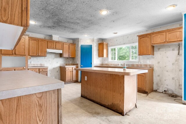 6314 Providence Church Rd, Vale, NC 28168 - kitchen with a center island, under cabinet range hood, wallpapered walls, light floors, and a textured ceiling