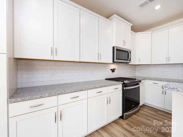1206 Pebble Grove Dr, Clover, SC 29710 - kitchen featuring appliances with stainless steel finishes, white cabinets, light wood-style flooring, decorative backsplash, and recessed lighting