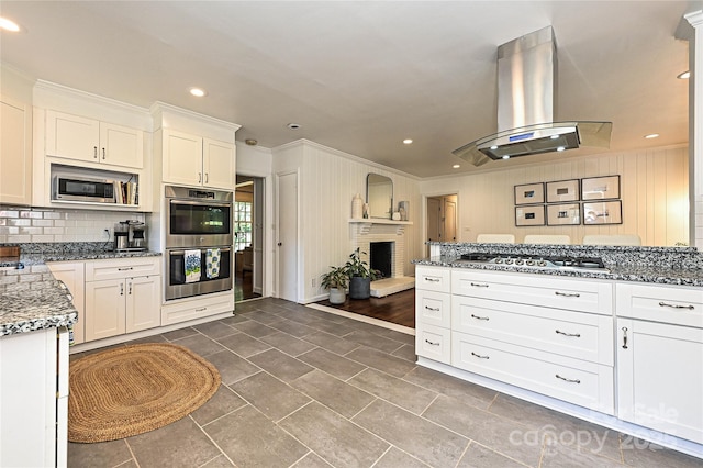 5301 Addison Dr, Charlotte, NC 28211 - kitchen featuring stainless steel appliances, wall chimney range hood, crown molding, stone countertops, and a brick fireplace