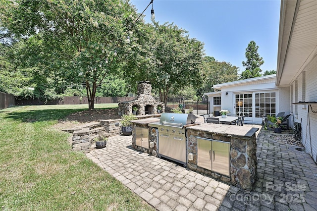 5301 Addison Dr, Charlotte, NC 28211 - fenced backyard featuring a patio area, an outdoor kitchen, an outdoor stone fireplace, and french doors